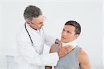 Male doctor examining a patients neck in the medical office