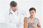 Male doctor injecting a patients arm in the medical office
