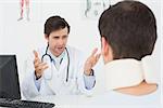 Male doctor in conversation with patient at desk in medical office