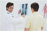 Portrait of a male doctor explaining spine x-ray to patient in the medical office