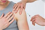 Close-up of hands injecting a young male patients arm over white background