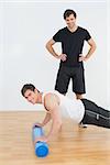 Portrait of physical therapist with young man doing push ups in the gym at hospital