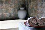 Two white rolled towels in a bathing room