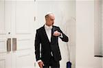 Anxious, Jewish Bridegroom standing in front of temple doors, looking at watch on Wedding Day, Canada