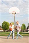 Couple playing basketball in neighbourhood park, Toronto, Ontario, Canada