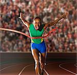 Young woman sprinting through winners tape in stadium