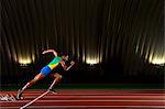 Young woman sprinting from starting blocks in stadium