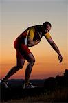 Young man preparing to throw shot put at sunset