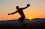 Young man preparing to throw discus at sunset