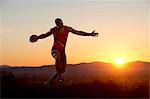 Young man preparing to throwing discus at sunset