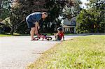 Grandfather picking up young boys bicycle