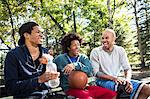 Young men sitting on park bench laughing