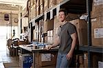 Worker standing in warehouse, leaning against shelving