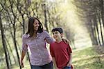 A woman and a child walking down an avenue of trees.