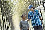 A man and a young boy walking down an avenue of trees.