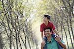 A boy having a piggyback, riding on a man's shoulders.