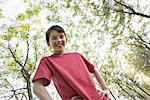 A young boy in the woodland, looking around curiously.