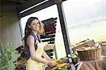 An organic fruit and vegetable farm. A young woman sorting vegetables.