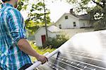 A man using a plan to place a solar panel in a farmhouse garden.