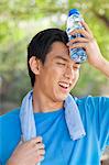 Young Man with Water Bottle after Exercising in Park