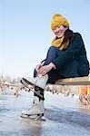 Young Woman Tying Ice Skates Outside