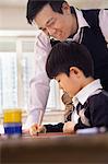 Teacher helping schoolboy with arts and crafts, Beijing