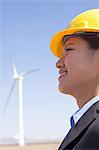 Portrait of young smiling female engineer checking wind turbines on site, side view