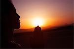 Serene young woman with hands together in prayer pose  in the desert in China, silhouette, sun setting