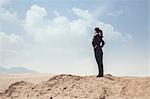 Young businesswoman standing with hands on hips looking out over the desert