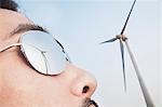 Close up of young mans face with the reflection of the wind turbine in his sunglasses