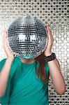 Young woman holding a disco ball in front of her face