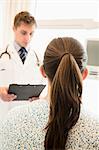 Doctor discussing medical chart with a patient sitting on a hospital bed