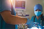 Midsection view of surgeon holding surgical equipment over the operating table