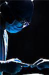 Two surgeons working and passing surgical equipment in the operating room, dark, close-up