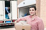 Smiling man holding a cardboard box and moving into his new home