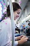 Young businesswoman sitting on the subway and using her phone