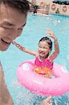 Little girl and her father splashing in the pool