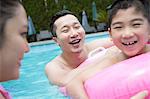 Smiling father, mother, and son playing in the pool