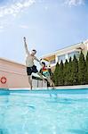 Father and daughter holding hands and jumping into the pool