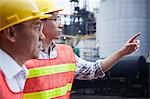 Two engineers in protective workwear pointing outside of a factory