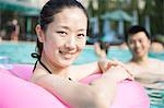 Portrait of smiling young women in the pool with an inflatable tube