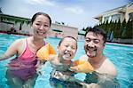 Portrait of smiling young family in the pool on vacation