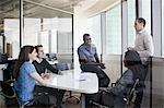 Five business people sitting at a conference table and discussing during a business meeting