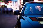 Smiling woman looking through car window at the city nightlife