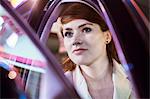 Serene businesswoman opening car door at night, close-up, reflected lights