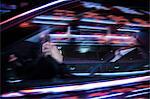 Businessman driving at night, illuminated and reflected lights on the car window