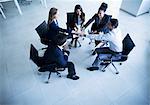 Business people sitting in a circle with hands together cheering