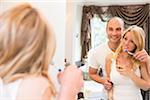 Young couple looking in bathroom mirror together, brushing teeth, Canada