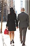 Backview of young couple in business wear, walking down city street, Toronto, Ontario, Canada
