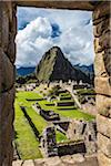Looking through stone, structural opening at overview of Machu Picchu, Peru
